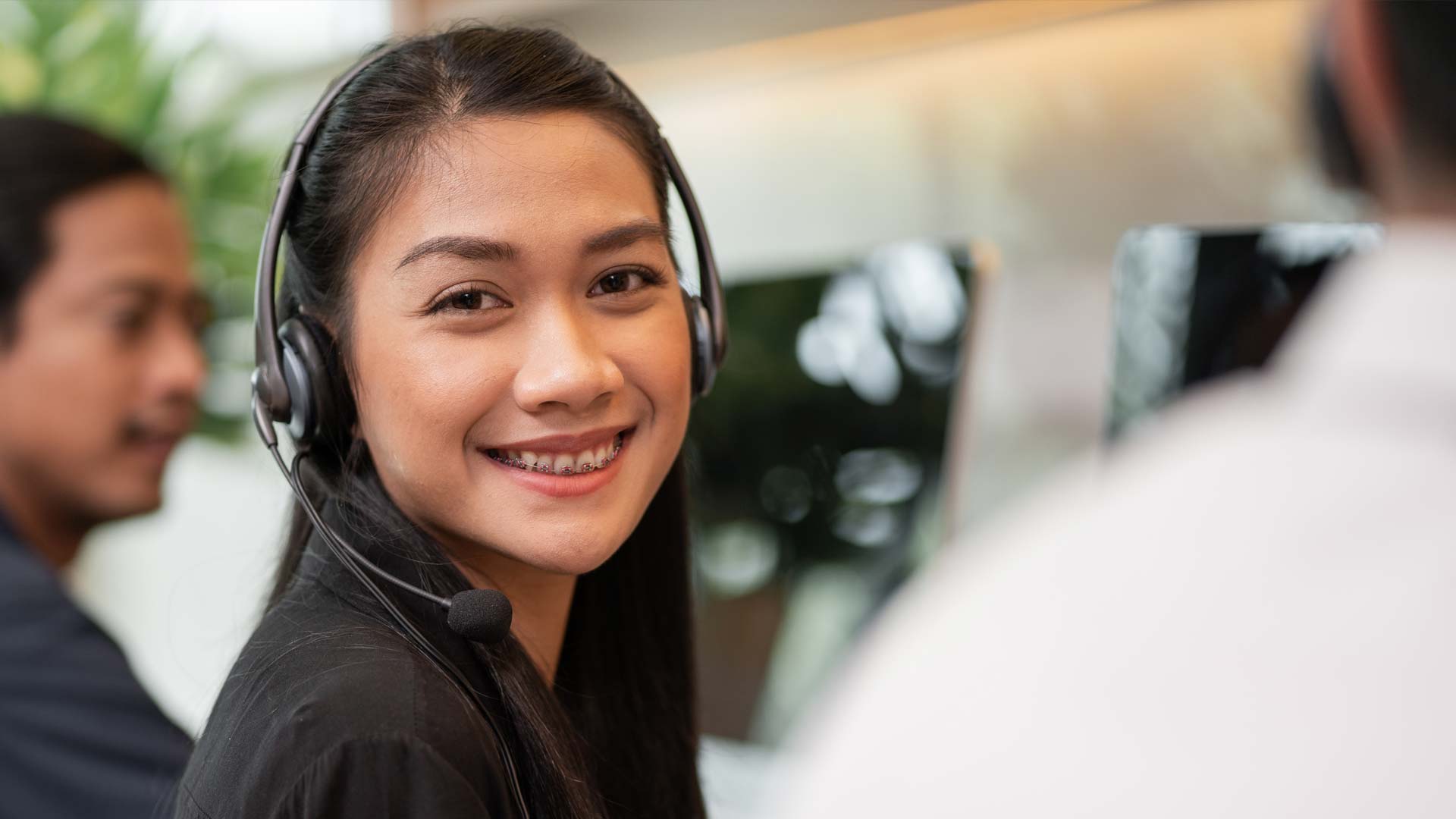 Asian female call center agent smiling at the camera while at work.