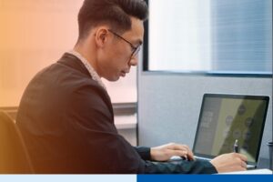 asian man in corporate attire typing in laptop in office