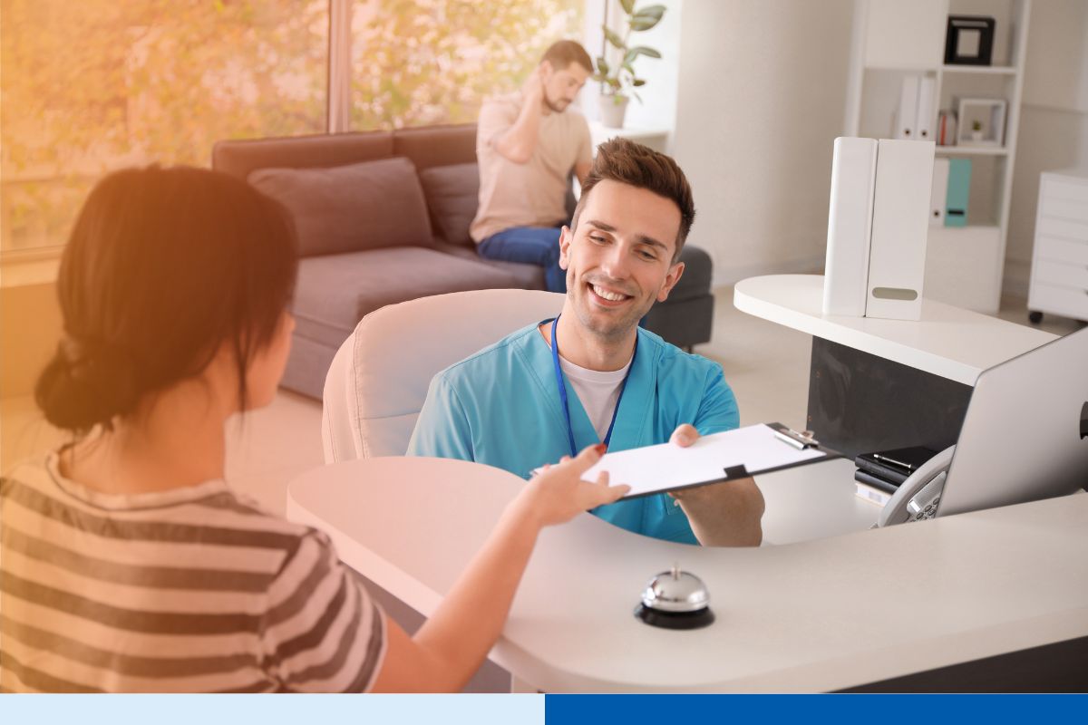 Front desk healthcare worker assisting patient with paperwork — highlights communication and workflow considerations in overcoming challenges in RCM offshoring.