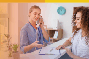 Receptionist at a vision center speaking on the phone while assisting a patient at the front desk.