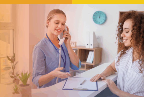 Receptionist at a vision center speaking on the phone while assisting a patient at the front desk.