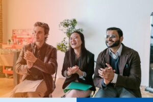happy people clapping in corporate attire in office meeting