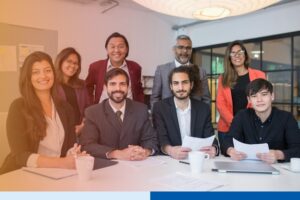 smiling people in corporate attire holding paperwork with tablets in office