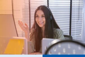 woman in corporate attire wearing a headset while using a laptop in office