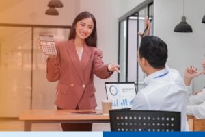 woman in office setting wearing corporate attire presenting while holding a calculator