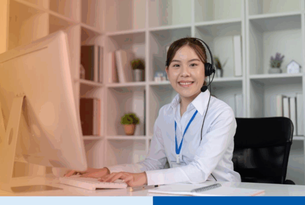 asian woman smiling with desktop n professional corporate attire smiling with office background