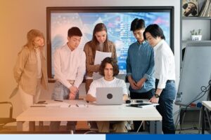 people in corporate attire discussing while using a laptop in an office