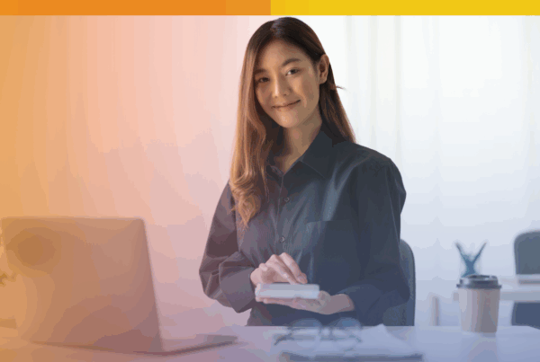 Smiling payroll professional using a calculator at her desk with a laptop, representing secure and efficient outsourced payroll support.