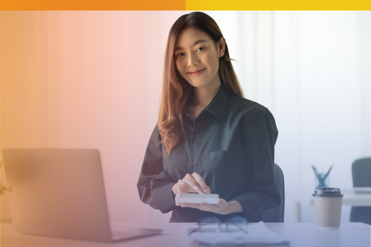 Smiling payroll professional using a calculator at her desk with a laptop, representing secure and efficient outsourced payroll support.