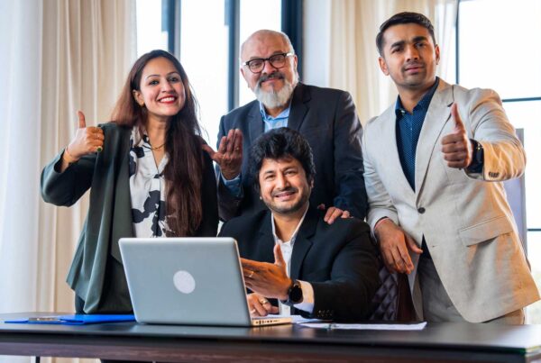 Team of Indian professionals smiling and giving thumbs up while working together at a laptop, representing reliable and collaborative outsourcing support in India.