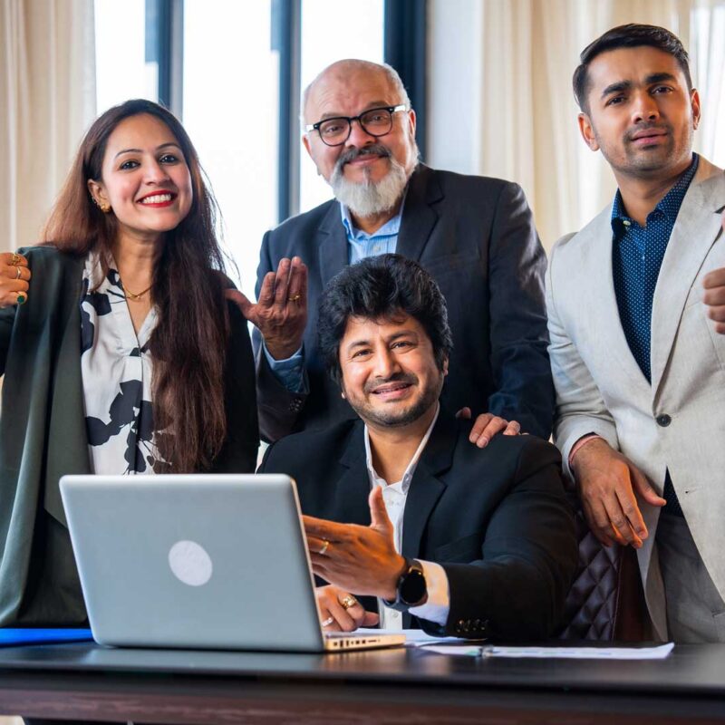 Team of Indian professionals smiling and giving thumbs up while working together at a laptop, representing reliable and collaborative outsourcing support in India.
