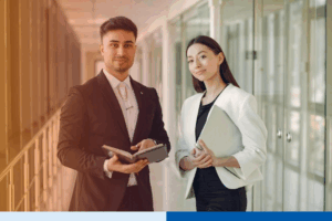 Professional businesspeople smiling while holding documents in office hallway representing BPO partnerships for business flexibility, operational visibility, and specialized skills access.