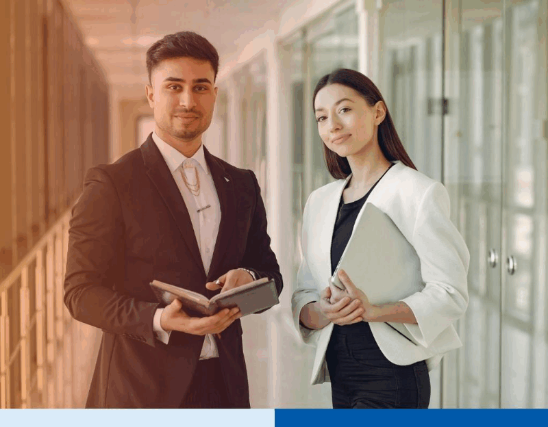 Professional businesspeople smiling while holding documents in office hallway representing BPO partnerships for business flexibility, operational visibility, and specialized skills access.