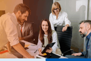 Group of business professionals discussing documents and digital devices in a modern office meeting, representing collaboration during the BPO switching process.