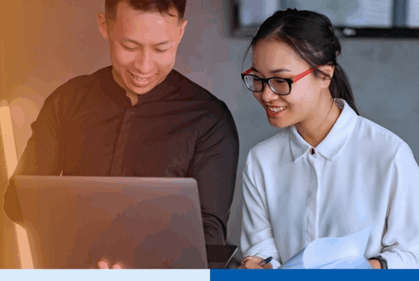 Two professionals, a man and a woman, collaborate happily on payroll outsourcing tasks using a laptop and documents in a modern office setting illustrating teamwork and efficiency in the Philippines payroll outsourcing industry for US firms in 2025