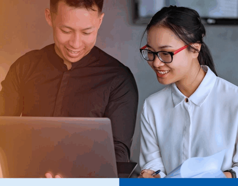 Two professionals collaborate on payroll outsourcing tasks using a laptop and documents in a modern office setting, illustrating teamwork and efficiency in the Philippines payroll outsourcing industry for U.S. firms in 2026.