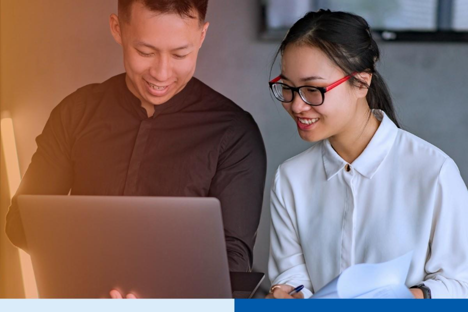 Two professionals collaborate on payroll outsourcing tasks using a laptop and documents in a modern office setting, illustrating teamwork and efficiency in the Philippines payroll outsourcing industry for U.S. firms in 2026.