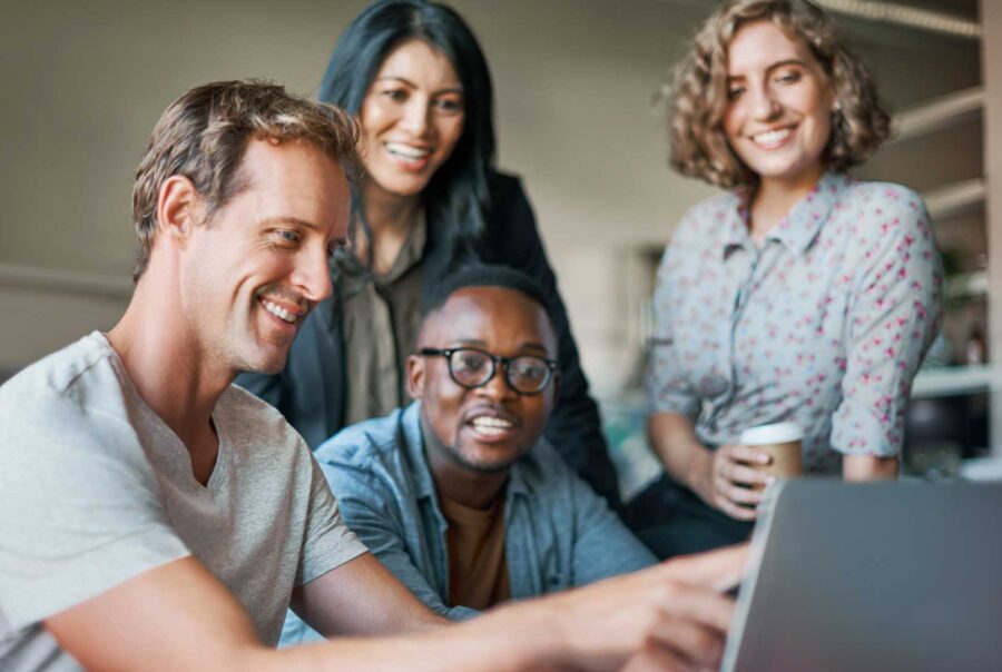 Team of software developers collaborating on a project using a laptop in a modern tech office environment.
