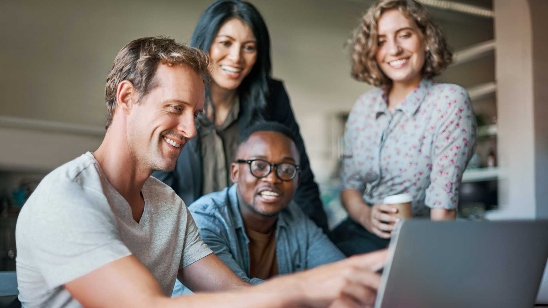 Team of software developers collaborating on a project using a laptop in a modern tech office environment.