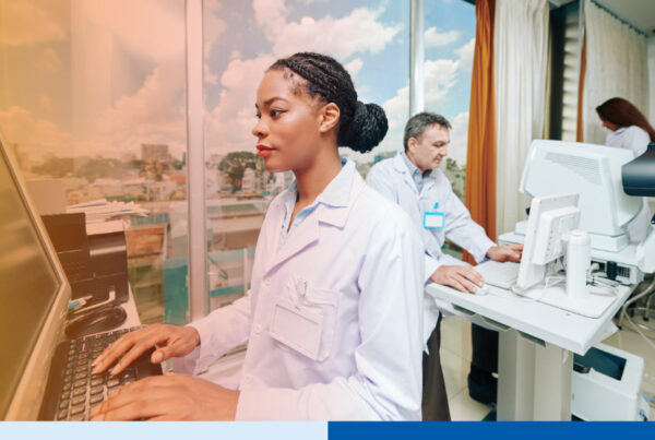 Healthcare professionals working at computers in a clinical technology setting.