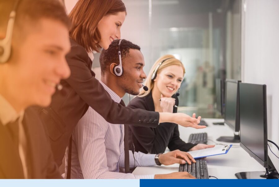 Customer service representatives wearing headsets collaborate while assisting customers at computer workstations.