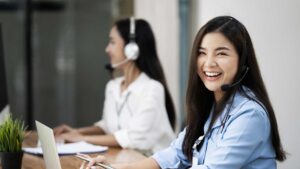 Cheerful women working in customer service with headsets.