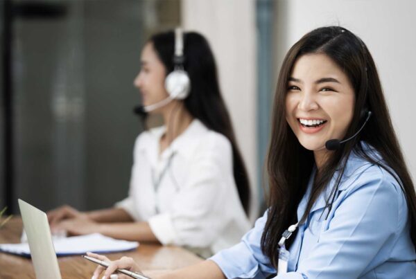 Cheerful women working in customer service with headsets.