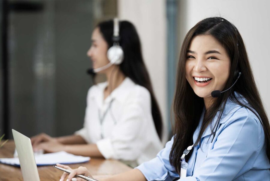 Cheerful women working in customer service with headsets.