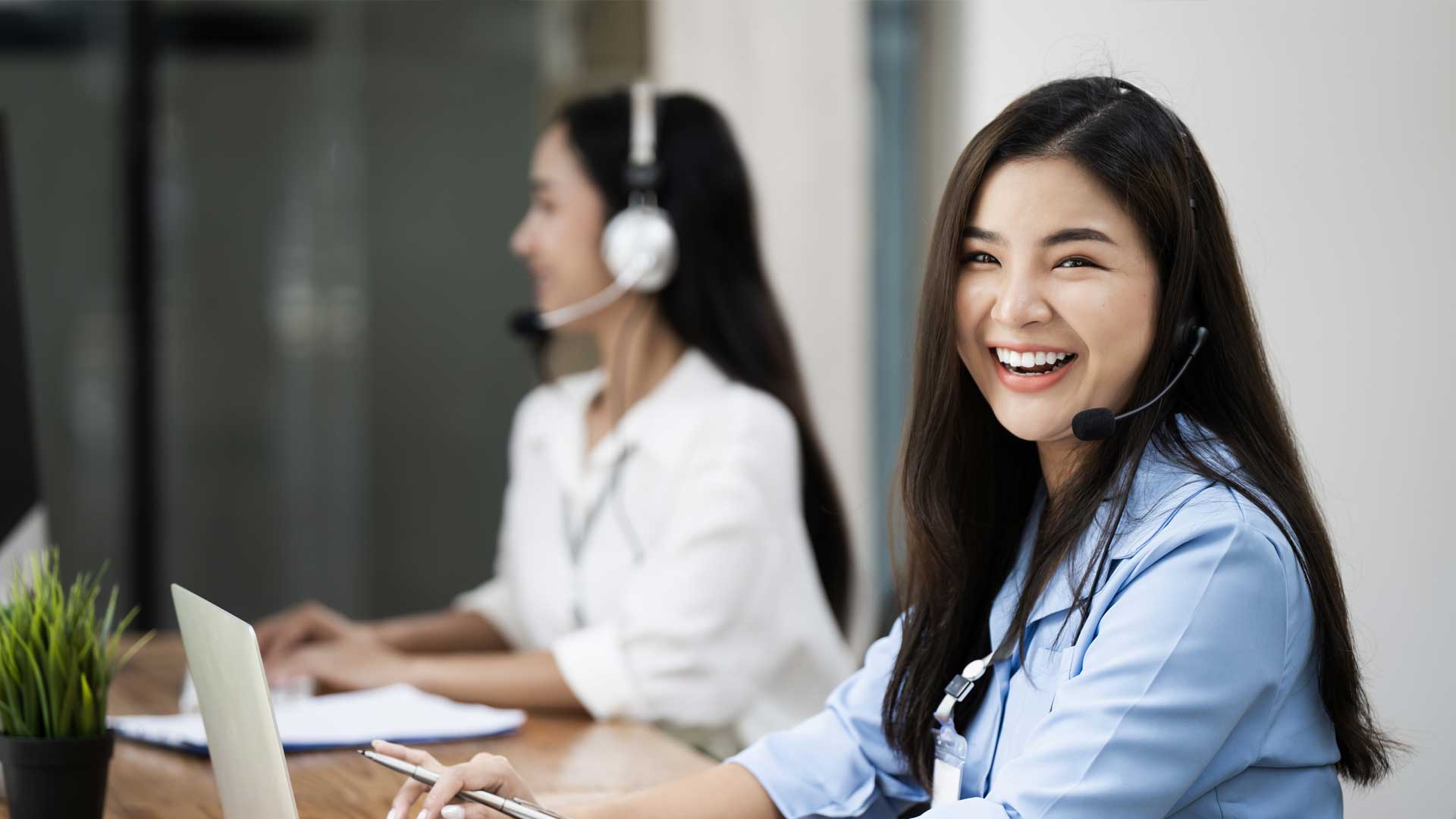 Cheerful women working in customer service with headsets.