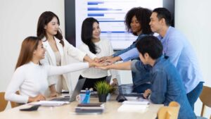 Diverse team members stacking their hands together during a collaborative office meeting.
