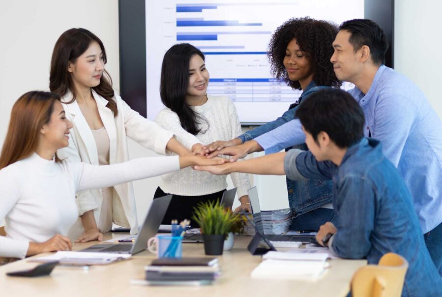 Diverse team members stacking their hands together during a collaborative office meeting.