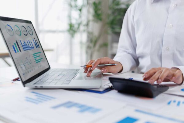 Image of a professional businesswoman analyzing financial reports with laptop and calculator.