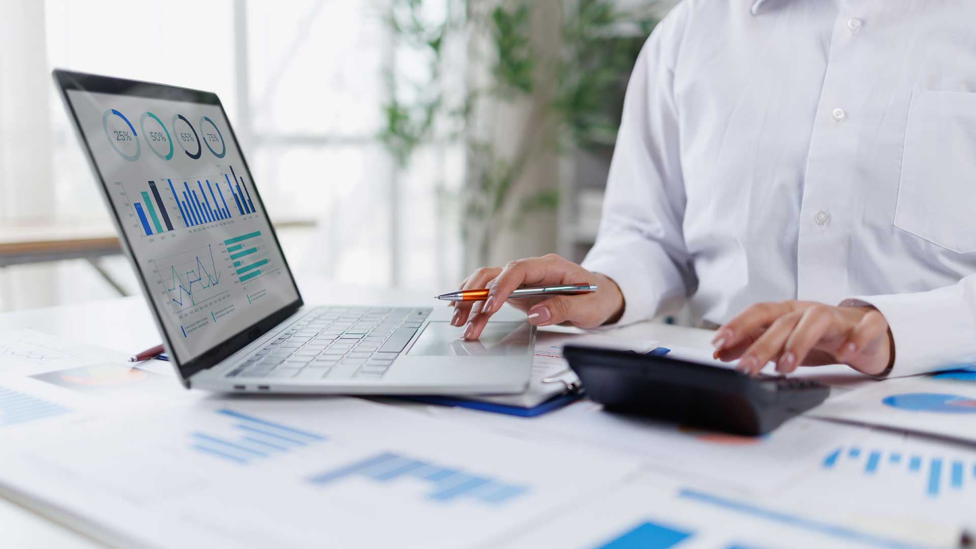 Image of a professional businesswoman analyzing financial reports with laptop and calculator.